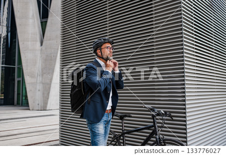 Urban commuter putting helmet on head before ride. Urban commuter putting helmet on head before ride. 133776027