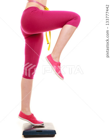 Woman with tape measure on weighing scale. Woman with tape measure on weighing scale. 133777442