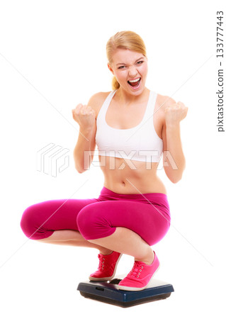 Happy successful woman weighing scale. Dieting. 133777443