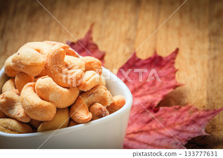 Cashew nuts in bowl on wooden background Cashew nuts in bowl on wooden background 133777631