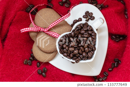 Coffee beans in heart shaped cup and dessert on red Coffee beans in heart shaped cup and dessert on red 133777649