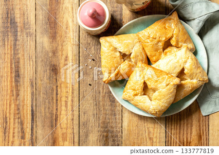 Puff pastry patties with mushroom and cheese filling on a rustic background. Top view. Puff pastry patties with mushroom and cheese filling on a rustic background. Top view. 133777819