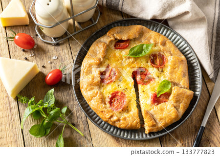 Crispy tomato galette with adyghe cheese and herbs on rustic background. 133777823