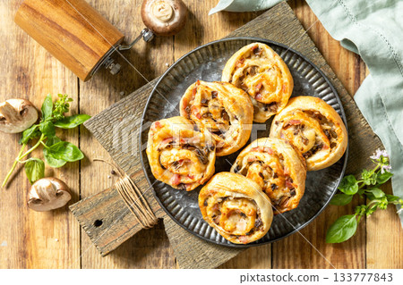 Puff pastry rolls with mushroom and cheese filling on rustic background. Top view. Puff pastry rolls with mushroom and cheese filling on rustic background. Top view. 133777843