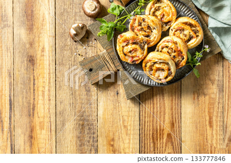 Puff pastry rolls with mushroom and cheese filling on rustic background. Top view. Puff pastry rolls with mushroom and cheese filling on rustic background. Top view. 133777846