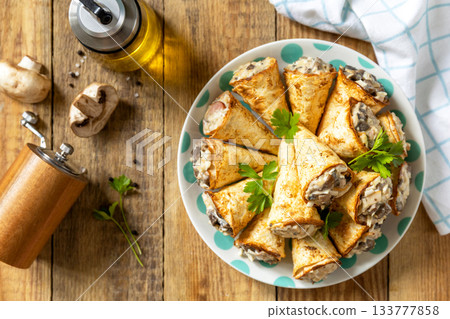 Crispy lavash rolls with mushroom filling, cheese and herbs on a rustic wooden table. Top view. Crispy lavash rolls with mushroom filling, cheese and herbs on a rustic wooden table. Top view. 133777858