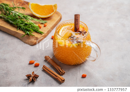 Sea buckthorn herbal tea in a cup on a light background with orange, spices and berries. Sea buckthorn herbal tea in a cup on a light background with orange, spices and berries. 133777957