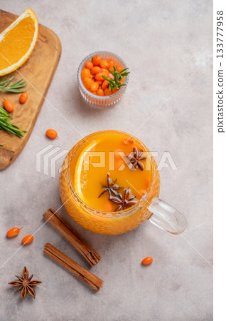 Sea buckthorn herbal tea in a cup on a light background with orange, spices and berries. 133777958