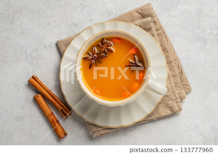 Sea buckthorn herbal tea in a cup on a light background with spices and napkin. 133777960
