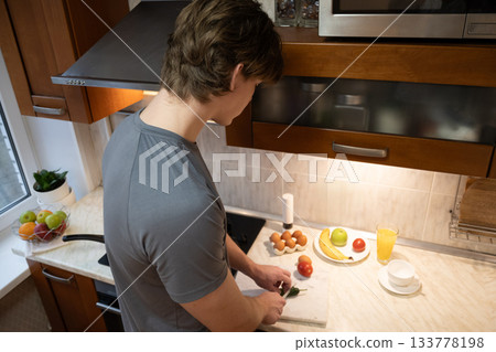 Cutting vegetables for breakfast by young man. Healthy Breakfast. Home Kitchen Lifestyle Cutting vegetables for breakfast by young man. Healthy Breakfast. Home Kitchen Lifestyle 133778198