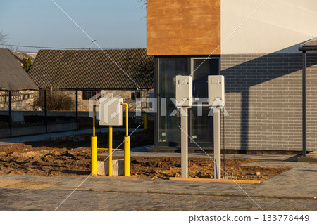 Exterior view of a newly built house with outdoor utility meters and yellow gas pipes installed 133778449
