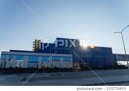 A large, modern industrial building with a vibrant blue facade A large, modern industrial building with a vibrant blue facade 133778455
