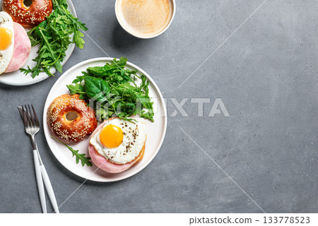 Healthy breakfast. Bagel sandwich with fried egg, ham and greens 133778523