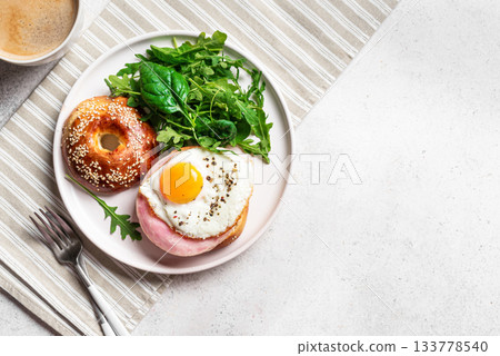 Healthy breakfast. Bagel with fried egg, ham and greens 133778540
