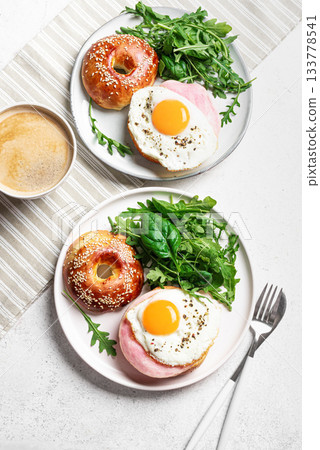 Healthy breakfast. Bagels with fried egg, ham and greens 133778541