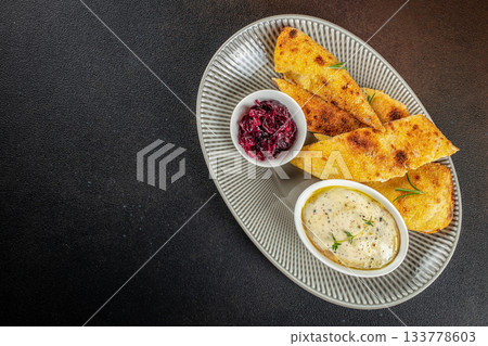 Crispy golden polenta bread served with creamy herb dip and sweet caramelized red onion on an elegant plate dark background copy space for restaurant menu or food advertising Crispy golden polenta bread served with creamy herb dip and sweet caramelized red onion on an elegant plate dark background copy space for restaurant menu or food advertising 133778603
