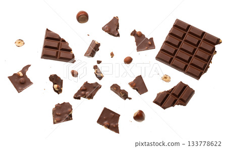 Scattered pieces of nut chocolate with whole hazelnuts isolated on white top view, perfect for confectionery advertising, dessert branding, packaging design and gourmet sweet food concepts Scattered pieces of nut chocolate with whole hazelnuts isolated on white top view, perfect for confectionery advertising, dessert branding, packaging design and gourmet sweet food concepts 133778622