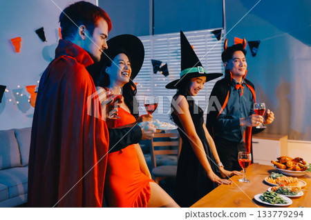 Joyful office Halloween party with coworkers in costumes, celebrating with drinks and laughter, fostering teamwork and festive spirit 133779294