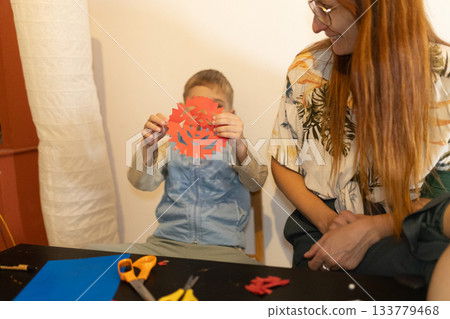 Child presenting handmade paper snowflake to adult Child presenting handmade paper snowflake to adult 133779468