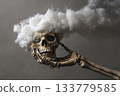 Skeletal hand gripping skull while clouds form in the background 133779585