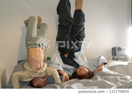 Mother and child playing upside down on bed enjoying family fun 133779604