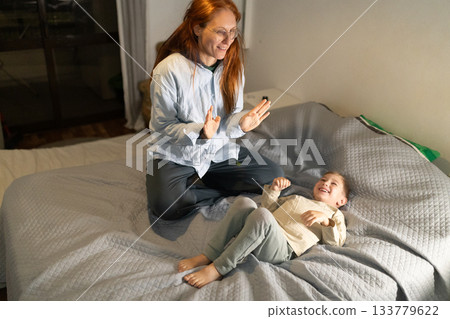 Mother and child playing together in bedroom 133779622