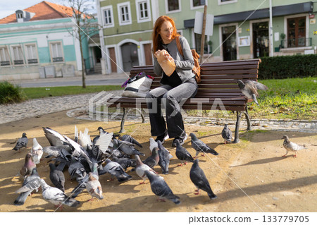 Woman feeding pigeons in city park, enjoying nature Woman feeding pigeons in city park, enjoying nature 133779705