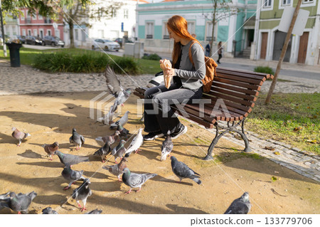 Woman feeding pigeons in urban city park Woman feeding pigeons in urban city park 133779706