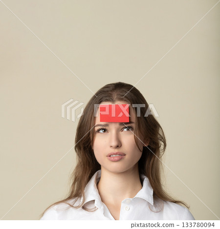Woman with red sticker note on her forehead 133780094