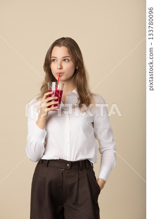 Beautiful woman drinking red juice with straw 133780096