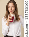 Beautiful woman drinking red juice with straw 133780100