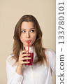 Beautiful woman drinking red juice with straw 133780101