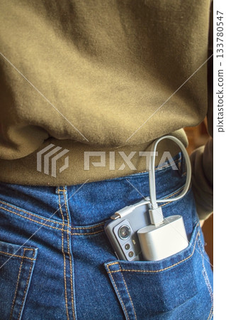 Charging the phone and external battery in the back pocket of jeans. Phone and portable charger in a denim pocket. Charging the phone and external battery in the back pocket of jeans. Phone and portable charger in a denim pocket. 133780547