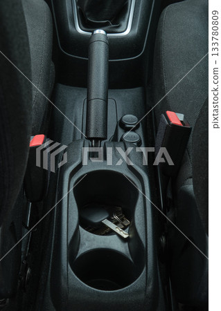 Car interior with keys in cupholder and handbrake 133780809