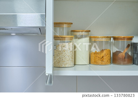Pantry cabinet organizing dry food ingredients in glass jars 133780823