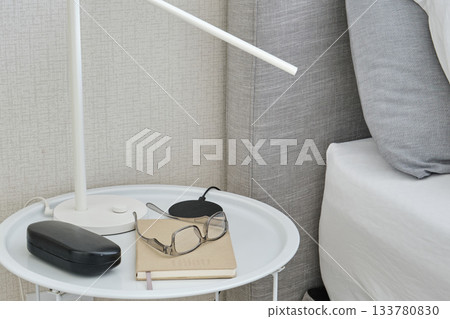 Bedside table with lamp, glasses, and notebook Bedside table with lamp, glasses, and notebook 133780830