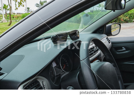 Sunglasses sitting on car dashboard driving on road trip Sunglasses sitting on car dashboard driving on road trip 133780838