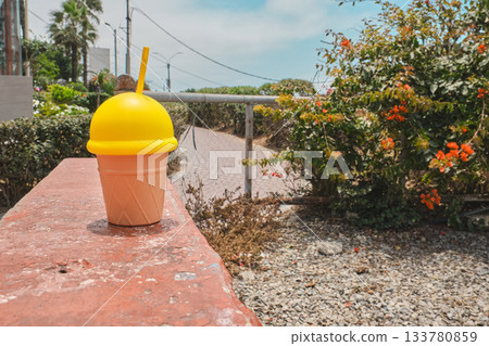 Yellow ice cream cone cup on a sunny outdoor wall 133780859