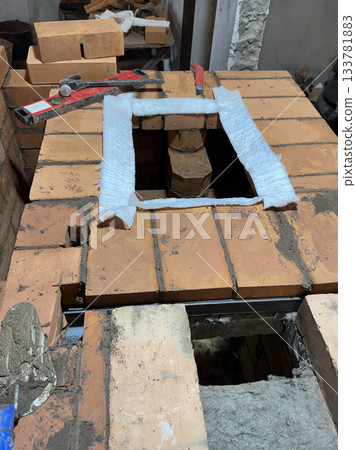 Preparing the site for installation of the heating stove slab. Brickwork during the construction of a heating stove. Preparing the site for installation of the heating stove slab. Brickwork during the construction of a heating stove. 133781883