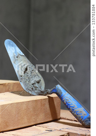 A masonry trowel with remnants of clay mixture for heating stove bricklaying. Close-up. A masonry trowel with remnants of clay mixture for heating stove bricklaying. Close-up. 133781884