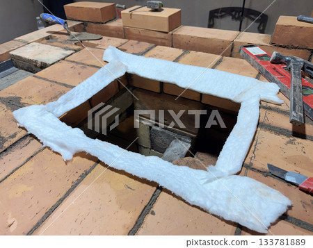 Preparing the site for installation of the heating stove slab. Brickwork during the construction of a heating stove. Close-up. Preparing the site for installation of the heating stove slab. Brickwork during the construction of a heating stove. Close-up. 133781889