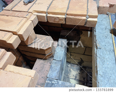 Brickwork of a heating stove. Channels for dividing and passing smoke. A fragment of the firebox with fireclay masonry. Close-up. 133781899