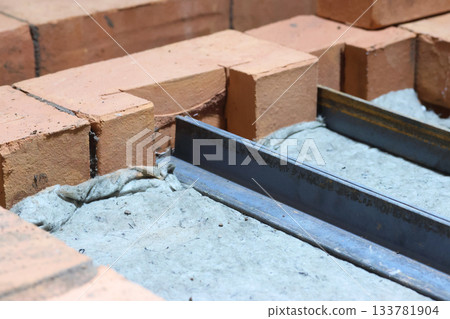 Installation of the heating stove ceiling. Insulation with mineral wool. Ceiling made of bricks on metal angles. Construction of a heating stove. Close-up. Installation of the heating stove ceiling. Insulation with mineral wool. Ceiling made of bricks on metal angles. Construction of a heating stove. Close-up. 133781904