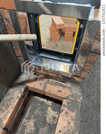 Construction of a heating stove. Brickwork of the stove core. The stove door in its frame is installed. The stove core is covered with mineral wool. Close-up. 133781921