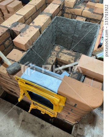 Construction of a heating stove. Brickwork of the stove core. The stove door in its frame is installed. The stove core is covered with mineral wool. Construction of a heating stove. Brickwork of the stove core. The stove door in its frame is installed. The stove core is covered with mineral wool. 133781922