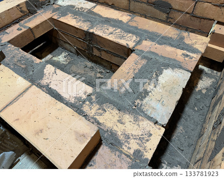 Construction of a heating stove. Brickwork of the stove core with its caps. Close-up. 133781923
