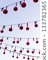Outdoor string lights with bulbs decorated with red Christmas balls 133782365