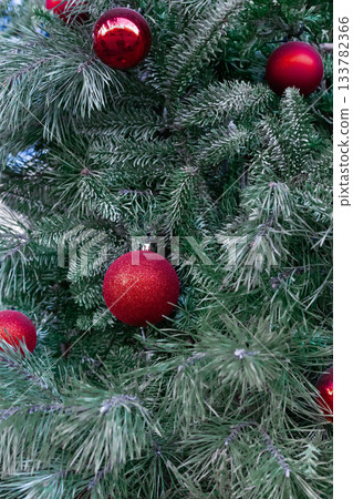 Red Christmas balls hanging on green pine branches. Red Christmas balls hanging on green pine branches. 133782366