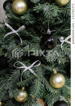 Christmas tree decorated with white bows and black and gold ornaments Christmas tree decorated with white bows and black and gold ornaments 133782371