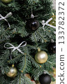 Close up of a tree branch with white bows and gold Christmas ornaments 133782372